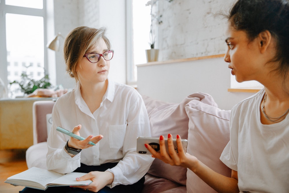 Woman getting feedback from a trusted friend, taking notes on how to improve her presentation.