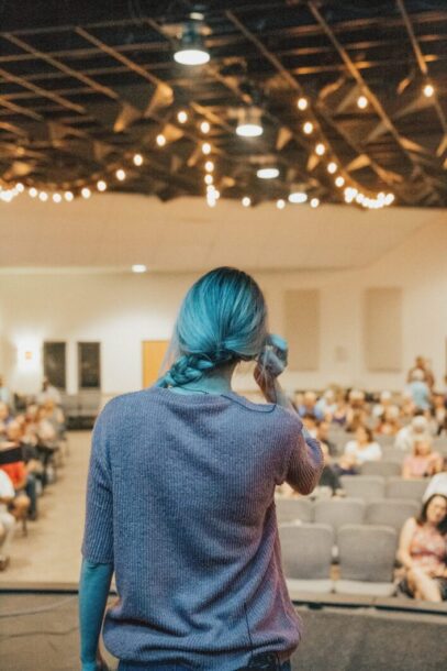 Introverted woman speaking before a crowd, desensitizing herself via frequent public speaking opportunities. 